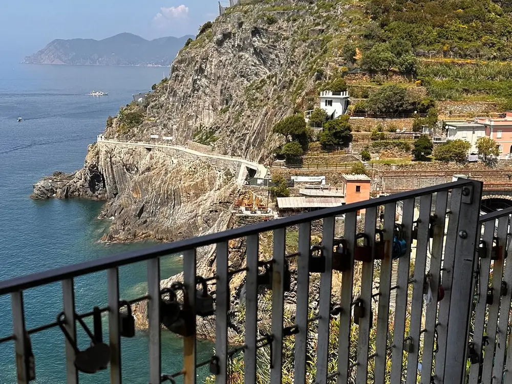 A railing hung with padlocks looking along a cliff path above the sea