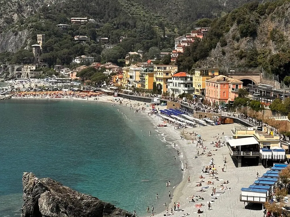 The curve of Monterosso's sandy beach with umbrellas and pastel houses behind