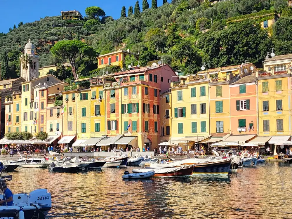 Tall yellow and orange houses along Portofino's harbour front with moored boats