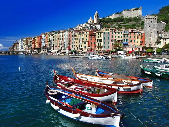 Wooden boats in the harbour of Portovenere below a row of tall coloured houses