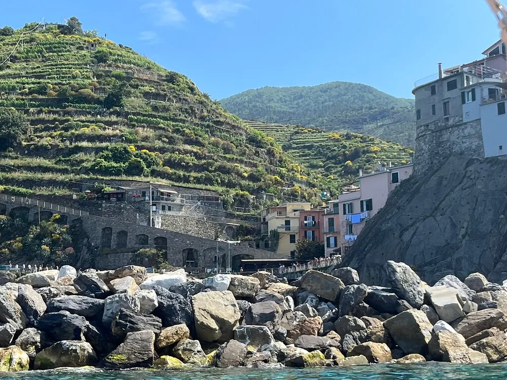 Terraced green hillsides above a rocky shore and the first houses of a village